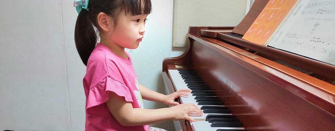 ピンク色の服の女の子がピアノを弾いている様子