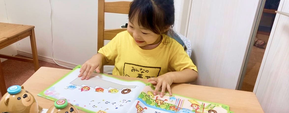 教材を笑顔でみる黄色の服をきた女の子